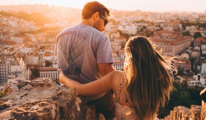 A couple hugging while looking at the sunset over a city in Europe