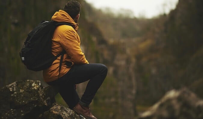 A man in a yellow coat looking out over the mountains