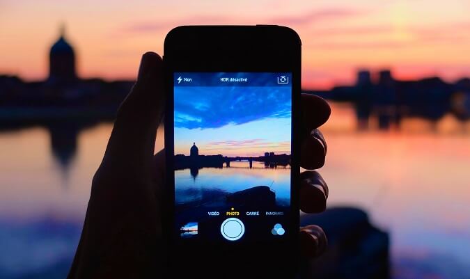 someone taking the picture of the sunset with their iphone