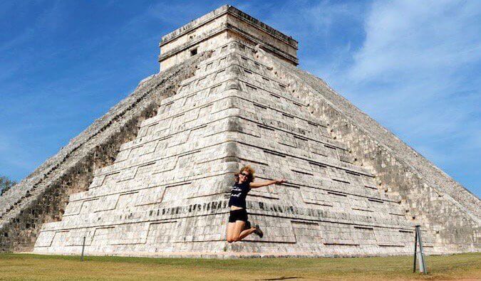 Woman jumping in front of Chichen Itza Mayan ruins in Mexico