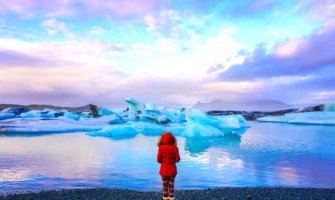 solo female traveler in a read coat at the Glacier Lagoon in Iceland