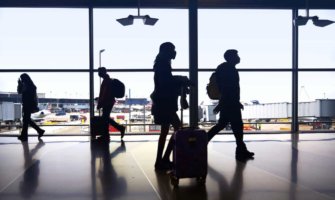 people silhouetted by a window at an airport