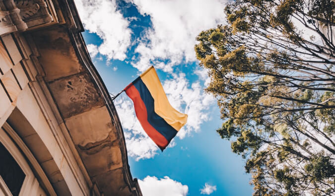 A colorful Colombian flag hanging from an old building.