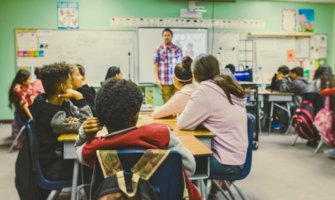 A man teaching English to a classroom of students abroad