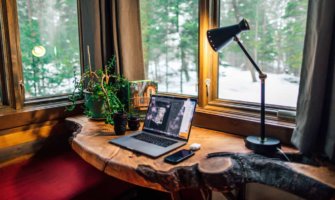 A cozy work from home office space with a laptop and camera lenses